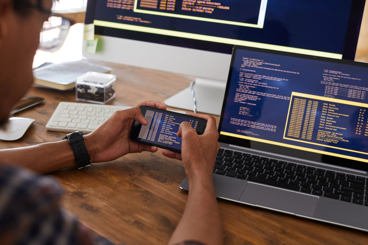 Software Developer Holding Smartphone at Workplace Close Up